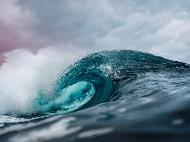 Ocean wave curling under a cloudy sky